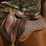 performance saddle pad, under saddle, in herringbone pattern with cognac trim. 