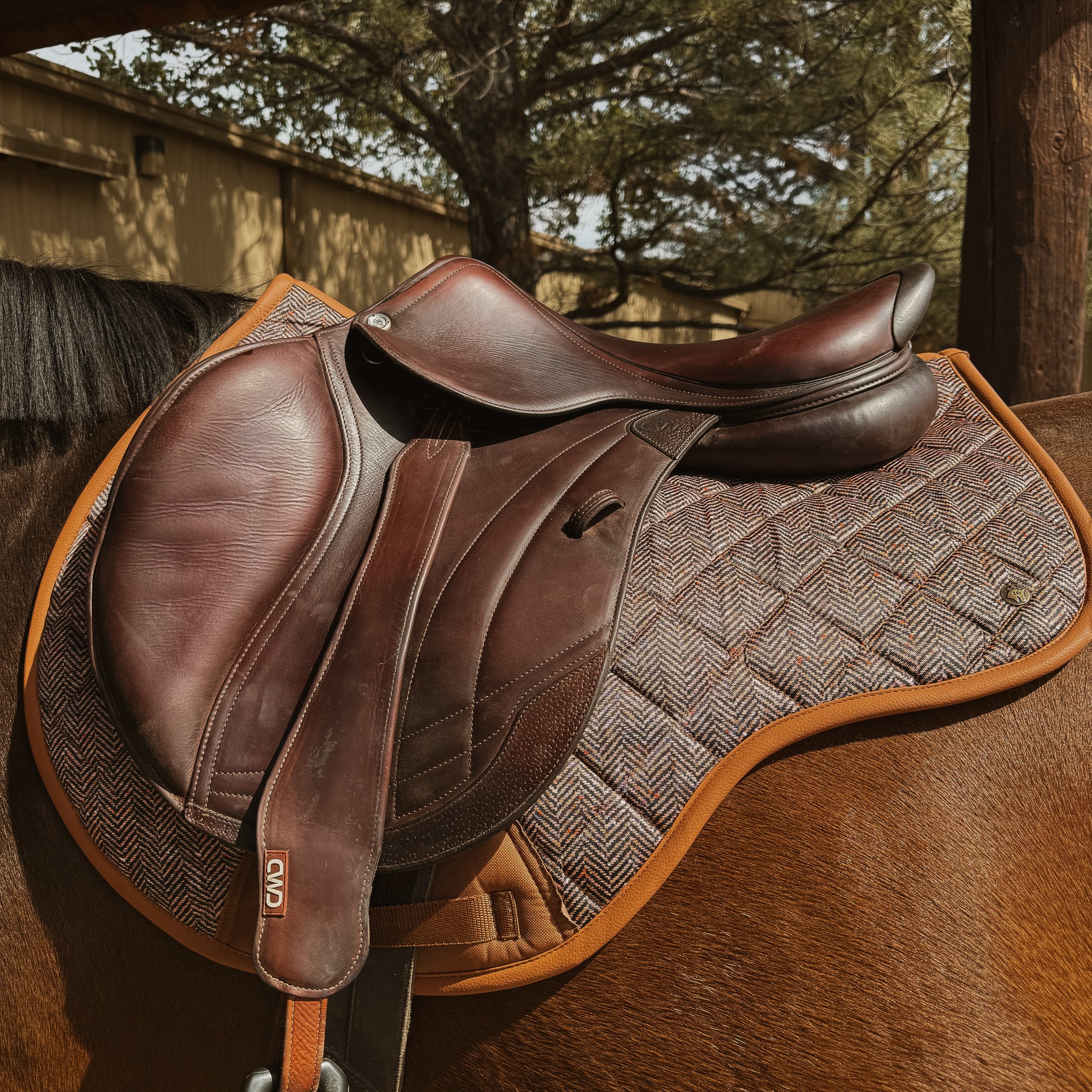 performance saddle pad, under saddle, in herringbone pattern with cognac trim. 