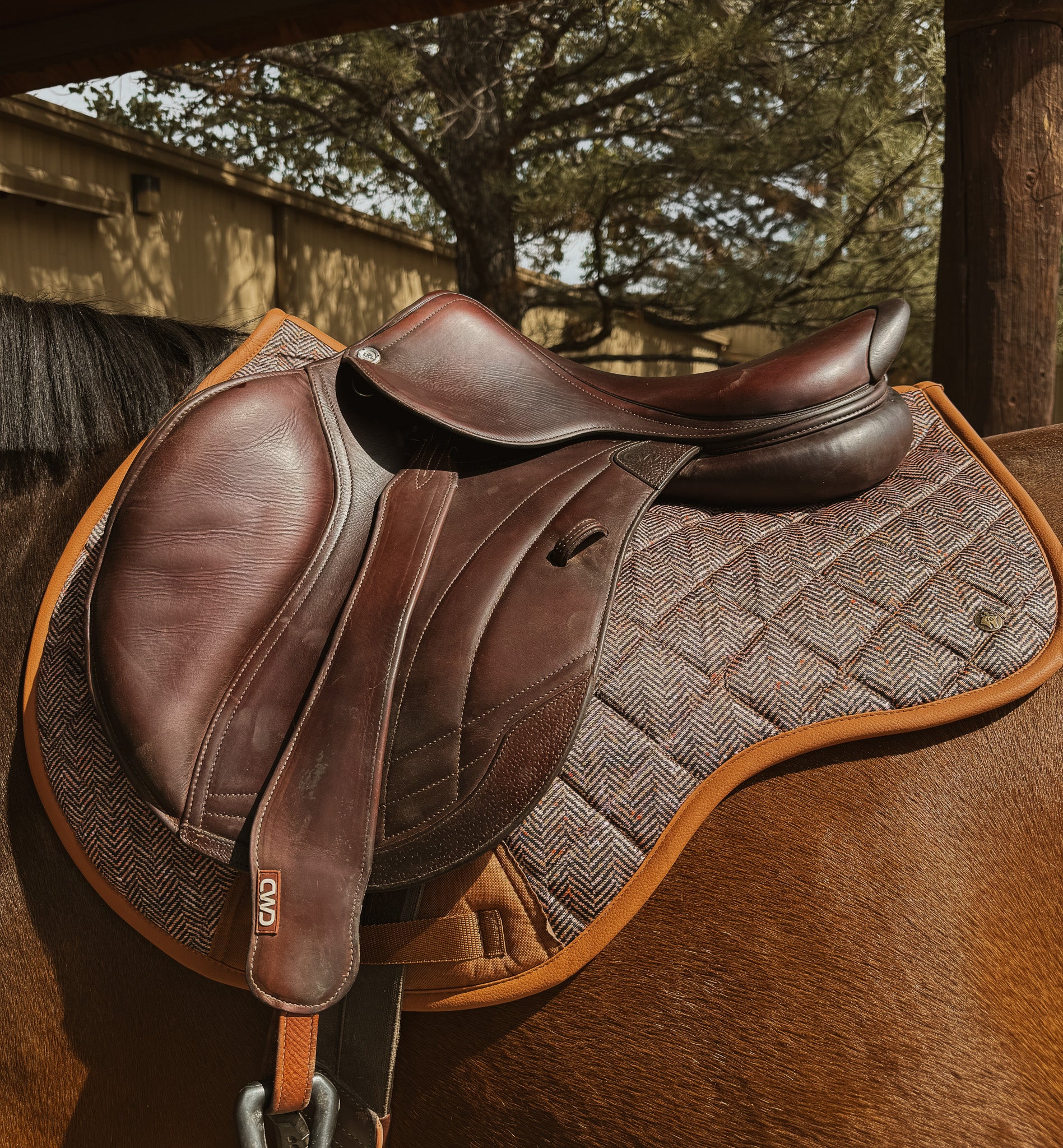 performance saddle pad, under saddle, in herringbone pattern with cognac trim. 