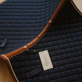 Navy quilted saddle pad with brown trim and Cypress Equestrian tag.