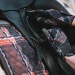 Person wearing sixteen cypress plaid gloves adjusting a saddle on a horse