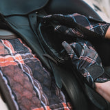 Person wearing sixteen cypress plaid gloves adjusting a saddle on a horse