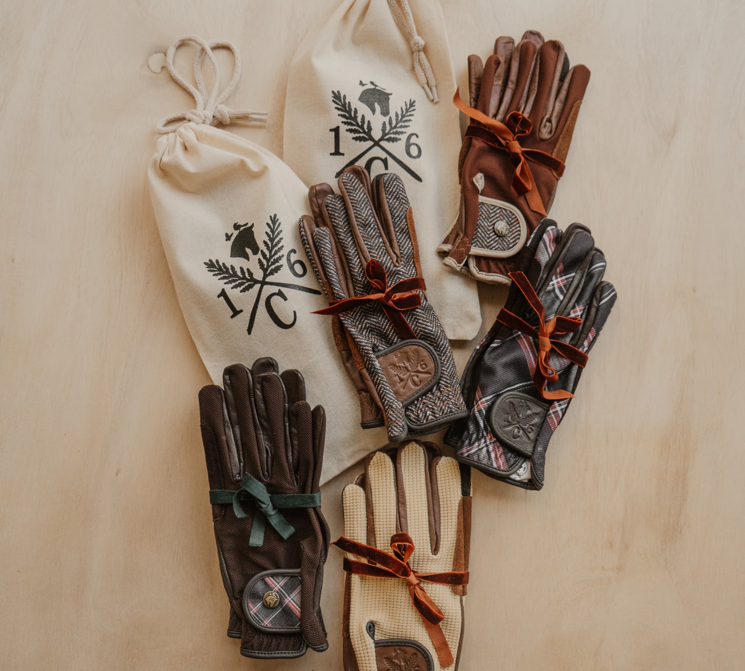 Pairs of leather gloves with drawstring bags on a wooden surface