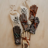 Pairs of leather gloves with drawstring bags on a wooden surface