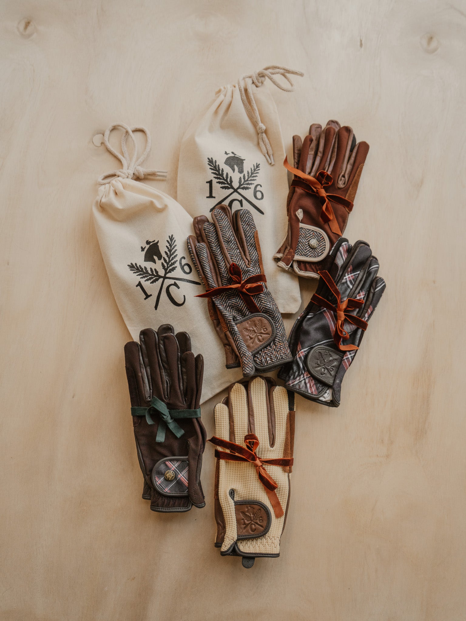 Pairs of leather gloves with drawstring bags on a wooden surface